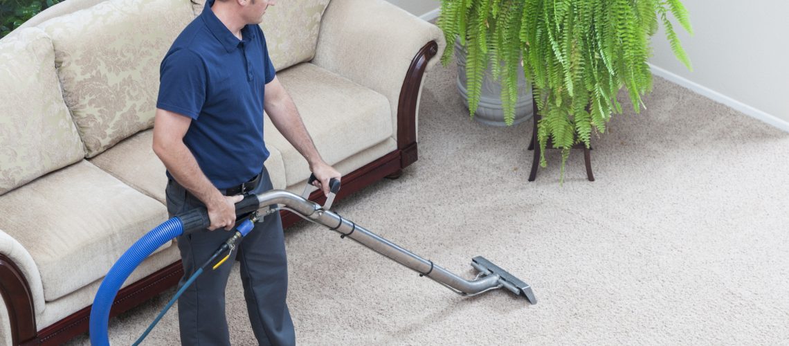 Professional carpet cleaner steam cleans a carpet in summer